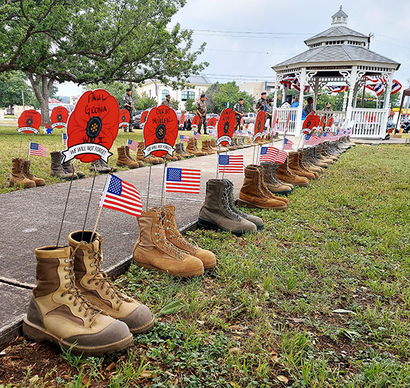 Pairs of military boots decorated with small American flags and the names of local fallen heroes written on red poppies line a walkway on the Kerr County Courthouse grounds in tribute to local service members who died in service to this great nation. - Photo by Kerr County Public Relations